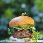 A juicy grilled lamb burger topped with feta cheese, tzatziki, pickles on a bun