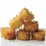 A stack of six homemade tater tots, sprinkled with sea salt.