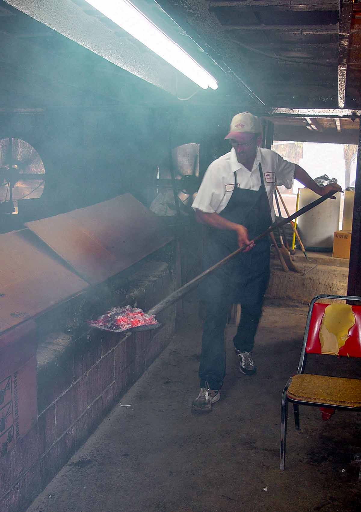 Ricky Parker shoveling hot coals into his barbecue smoker