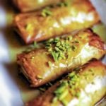 Four phyllo pastries stuffed with nuts, honey, and orange blossom water, and topped with pistachios and more honey