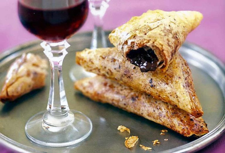 Crispy chocolate-filled pastry triangles and two glasses of dessert wine on a silver tray