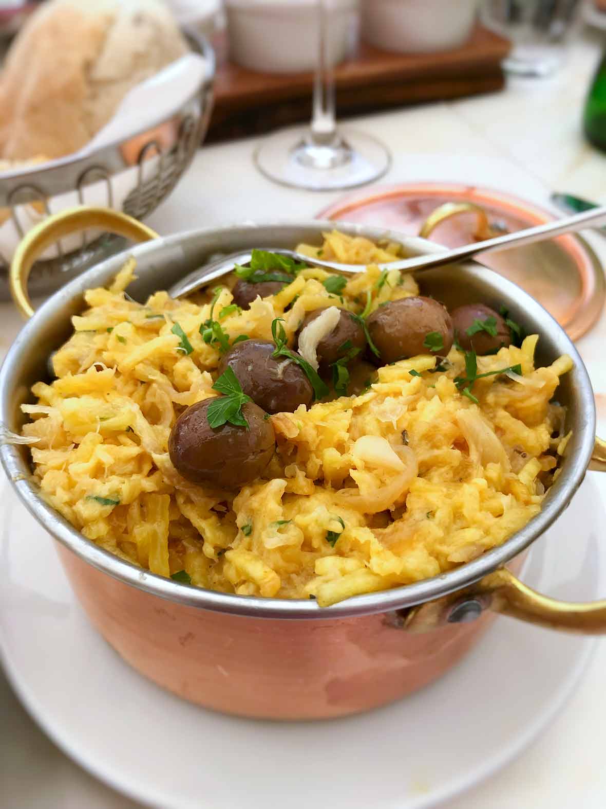 A copper pot of bacalhau a Bras--or Portuguese scrambled eggs, salt cod, potatoes, onions, olives, and parsley
