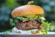 A juicy grilled lamb burger topped with feta cheese, tzatziki, pickles on a bun