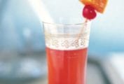 Red Singapore Sling with gin, cherry brandy, Benedictine, and triple sec in a tall glass with a cheery and pineapple skewer