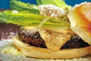 A Caesar salad burger--hamburger on a bun with melted cheese, Parmesan cheese, romaine lettuce and Caesar mayonnaise