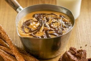 Pot of peanut butter chocolate fondue; pretzels and brownies, a glass of milk