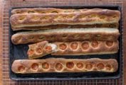 Five no-knead baguettes by Jim Lahey, some with sliced tomato, some with garlic and olives