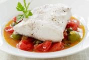 White bowl fill wth mahi mahi stewed with cherry tomatoes and capers in a broth