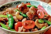 Bowl of cashew chicken with chunks of stir-fried chicken, carrots, sugar snap peas, celery, cashews