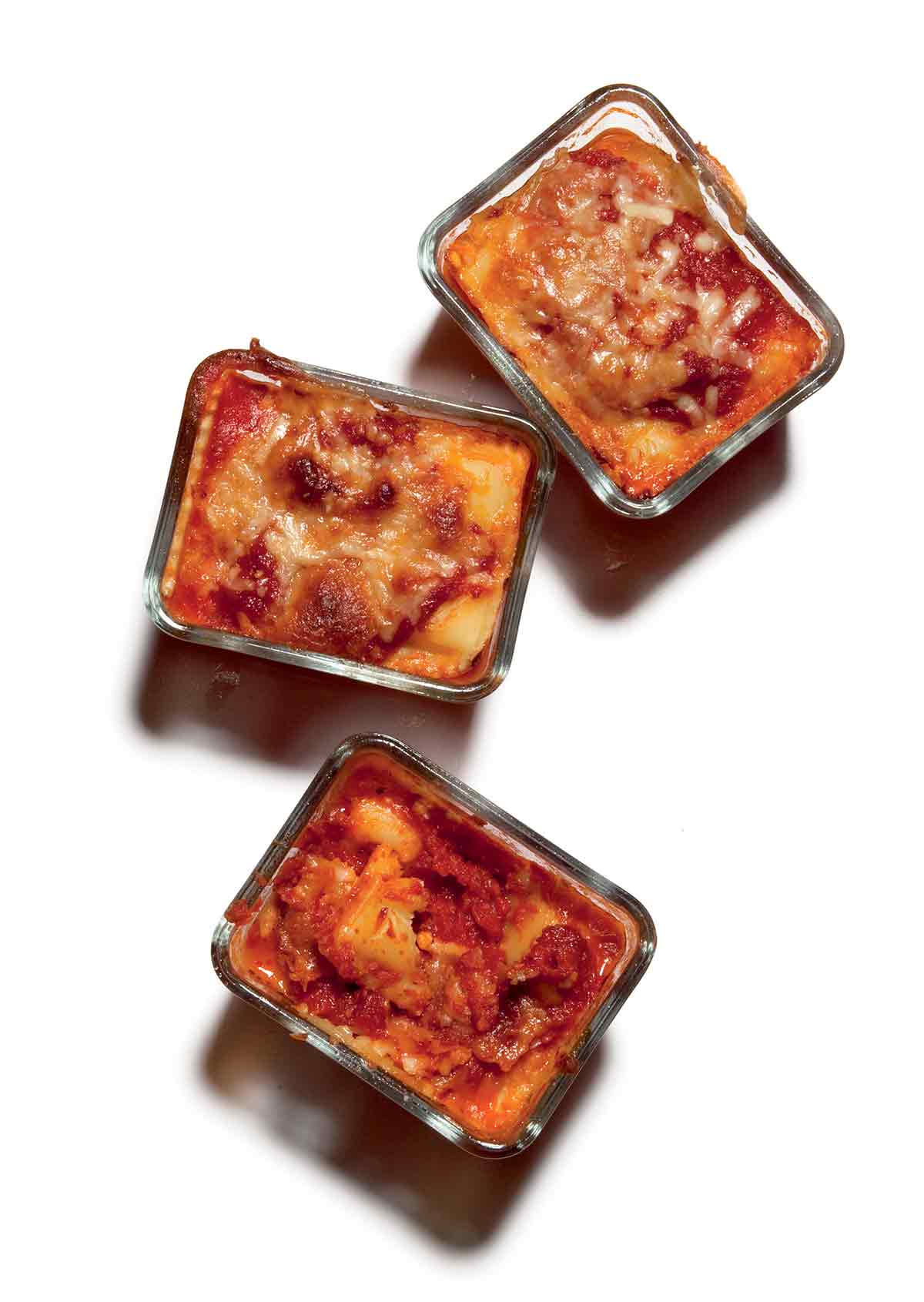 Three personal pan lasagnas in glass dishes.