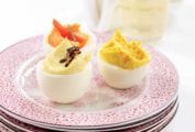 A plate with a trio of deviled eggs - horseradish deviled egg, truffled deviled egg, and smoked salmon deviled egg.