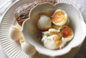 Halved soft-boiled eggs and toast on a plate with egg shells.
