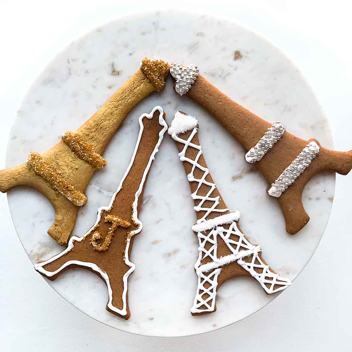 Four Swedish black pepper cookies called pepperkakor cut into Eiffel Tower shapes and decorated