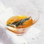 Sage brown butter with a crispy sage leaf in a small glass.