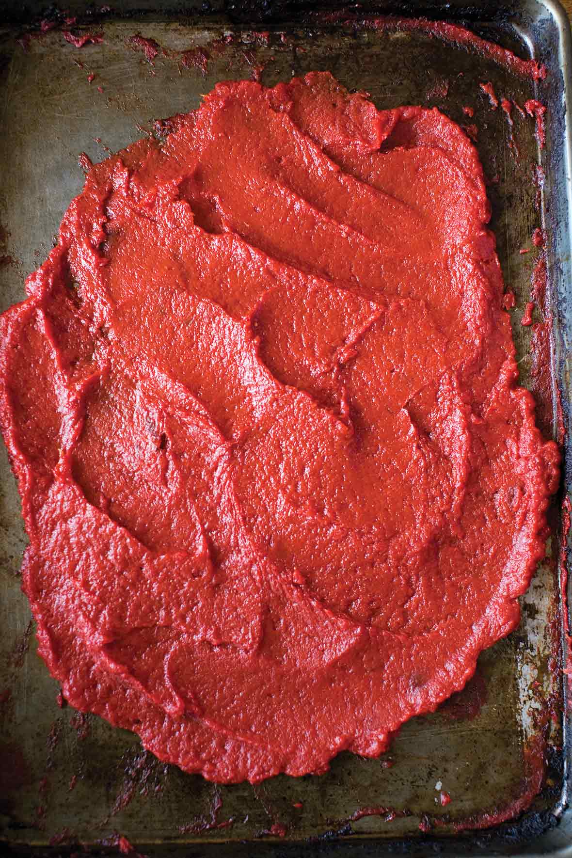 A rimmed baking sheet spread with a thick layer of homemade tomato paste.