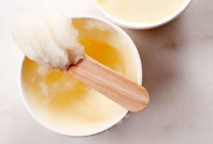 Two cardboard cups filled with lemon ice, one with a wooden spoon with of heap of ice on it
