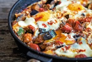 A skillet of eggs with chorizo and eggplant, tomato, zucchini, onion, and peppers.