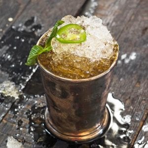 A jalapeno mint julep in a pewter julep cup, topped with a mint sprig and jalapeno slice.