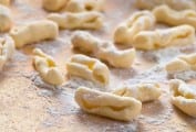 Pieces of uncooked homemade cavatelli on a floured surface.