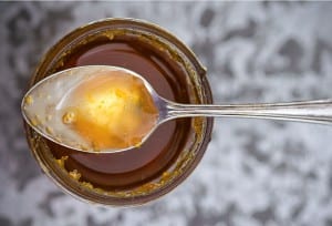 A jar of Meyer lemon syrup with a spoon resting on top.