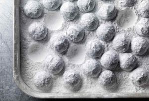 A rimmed sheet pan filled with truffles coated in confectioners' sugar