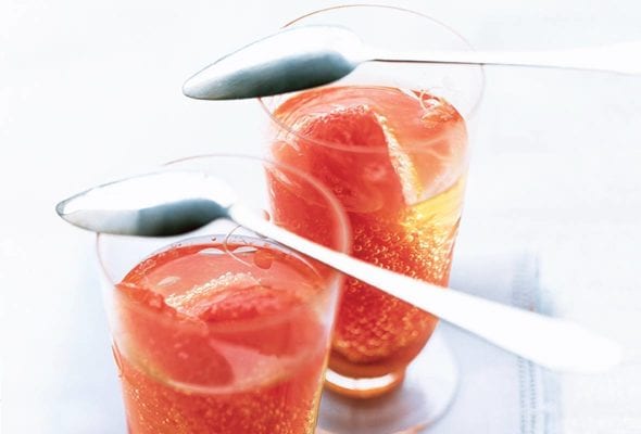 Two cordials glasses each filled with Moscato and a grapefruit section, on top are spoons