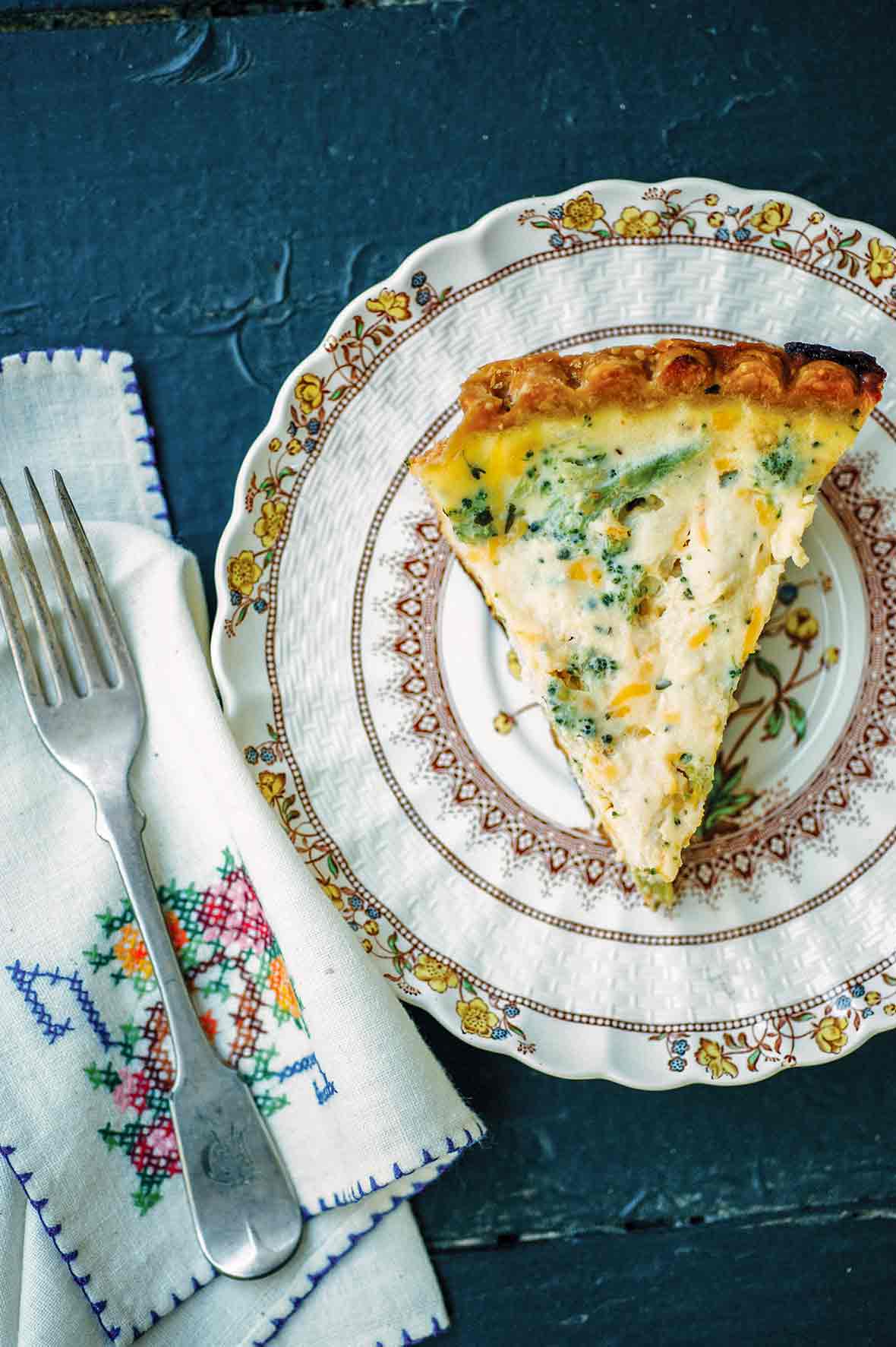 A plate with a slice of broccoli Cheddar quiche