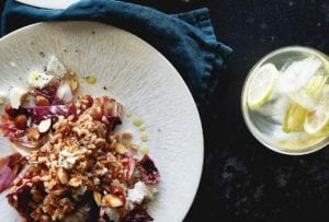 Two white plate of farro salad with radicchio and almonds, bowl of lemons, napkin