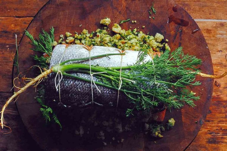 A whole herb stuffed baked salmon filled with bread crumbs and herbs and tied with kitchen twine.