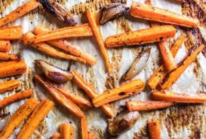 Baking sheet lined with parchment and covered with easy roasted carrots and onions with burnt edges