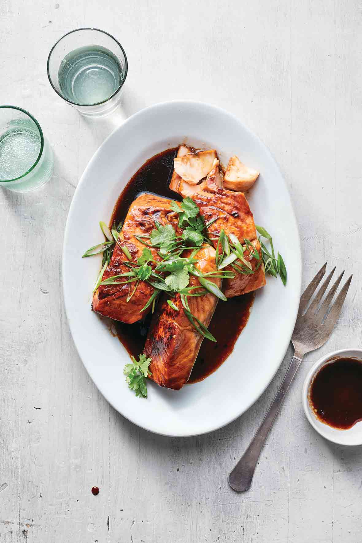 Pressure cooker Vietnamese caramel salmon, sliced green onion, and soy sauce on a white plate