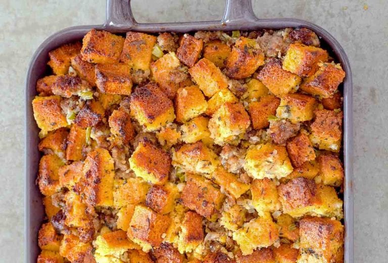 Casserole dish of cubes of homemade cornbread sausage dressing, with pork sausage, onion, celery, and spices