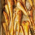 Sheet pan lined with parchment and sliced maple roasted parsnips