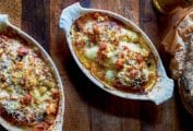 Two oval gratin dishes filled with braised endive gratin topped with bubbly browned cheese and breadcrumbs