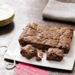 A square white platter with fruitcake brownies--filled with dried fruit, chocolate, and rum