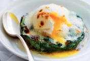 A white bowl with a easy eggs Florentine--a poached egg on top of a bed of cooked spinach