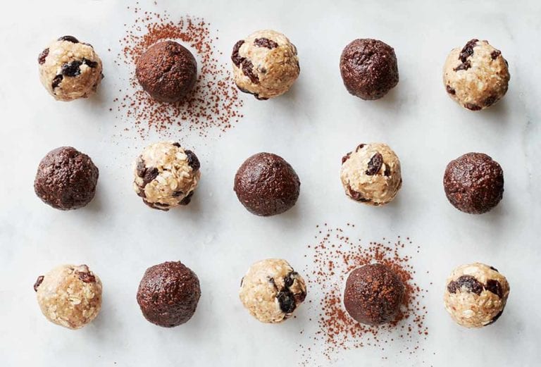 15 chocolate energy balls, made with dates, almond butter, almonds, and cacao powder, on white marble