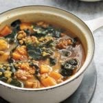 Bowl of red lentil soup with kale and chorizo, sweet potatoes, and onions