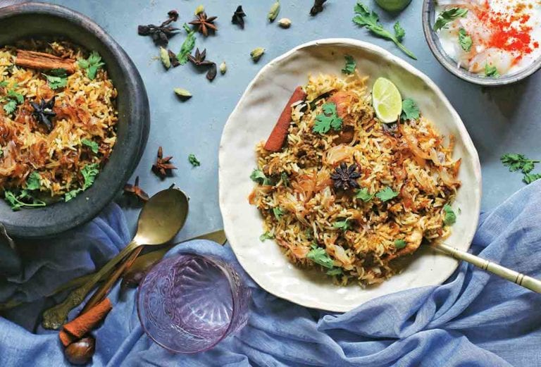 Two bowls filled with chicken biriyani on a blue cloth