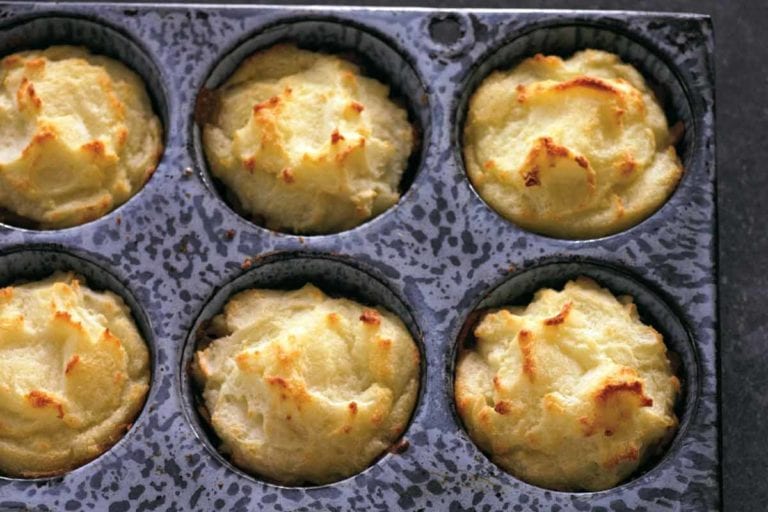 A muffin tin filled with cooked Thanksgiving leftovers muffins.