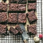 A batch of five ingredient Nutella brownies cut into squares on a wire rack with fresh raspberries scattered around.