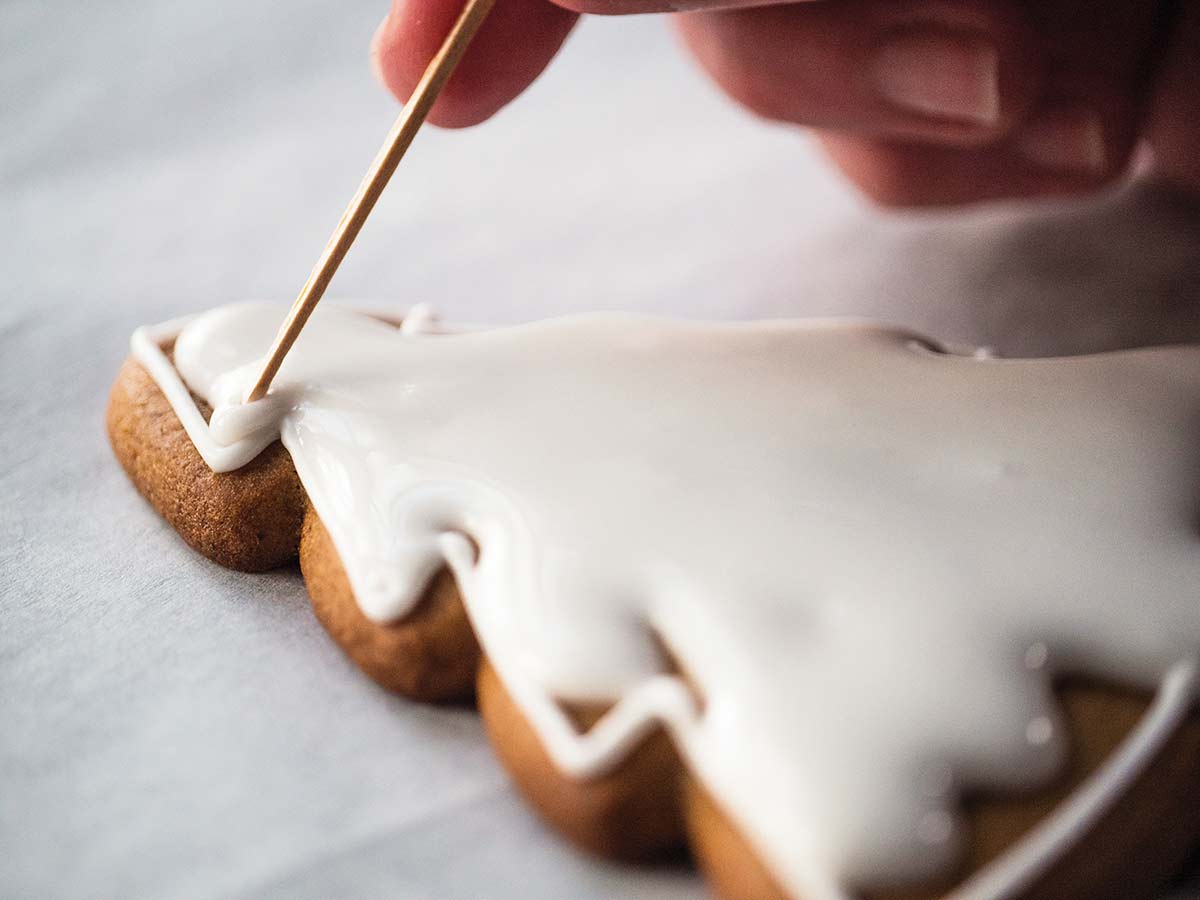 A tree-shaped cookie being filled with royal icing.