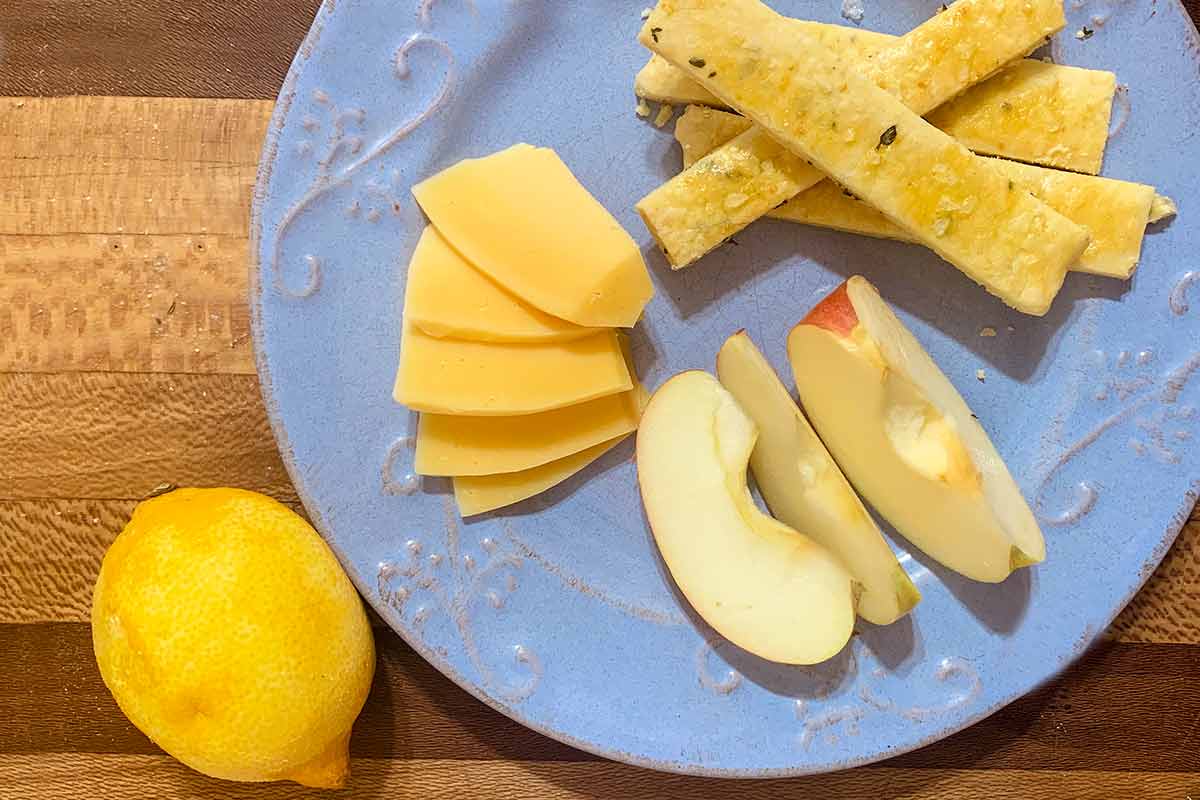 Savory thyme and lemon shortbread on a blue plate with apples and cheese