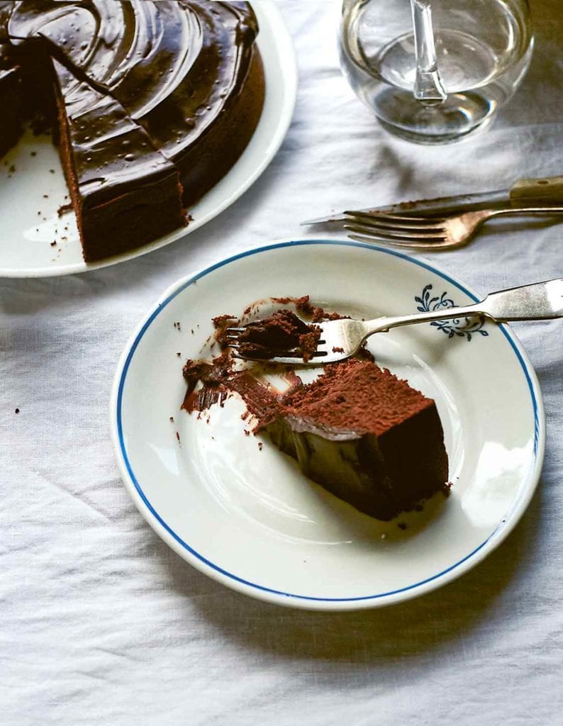 A partial slice of red wine chocolate cake on a plate with a fork resting beside the cake.
