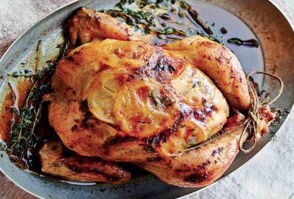 Roast chicken with lemon slices under the skin in a oval metal pan