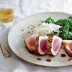A white plate with four slices of seared tuna with sweet and sour sauce, rice, and cooked greens.