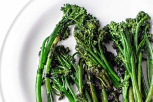 A white plate of skillet-charred broccolini.
