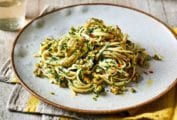 A gold-rimmed white plate topped with a serving of walnut parsley pesto pasta.