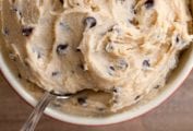 A bowl of eggless chocolate chip cookie dough with a spoon resting in it.