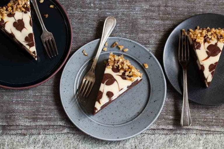 Three pieces of Junior's brownie swirl cheesecake on separate plates, each with a fork.